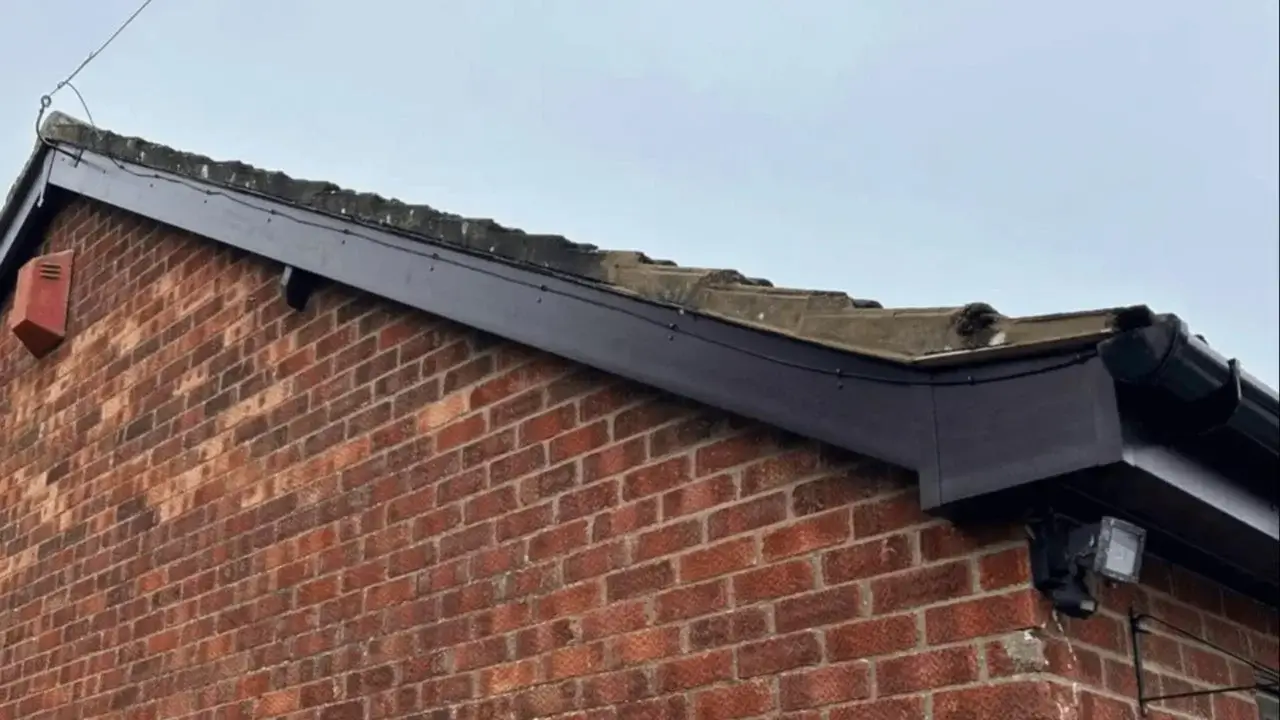 Clean installation of a dark grey fascia board along a red brick outbuilding roofline to protect against damp by Norfolk Exterior Solutions